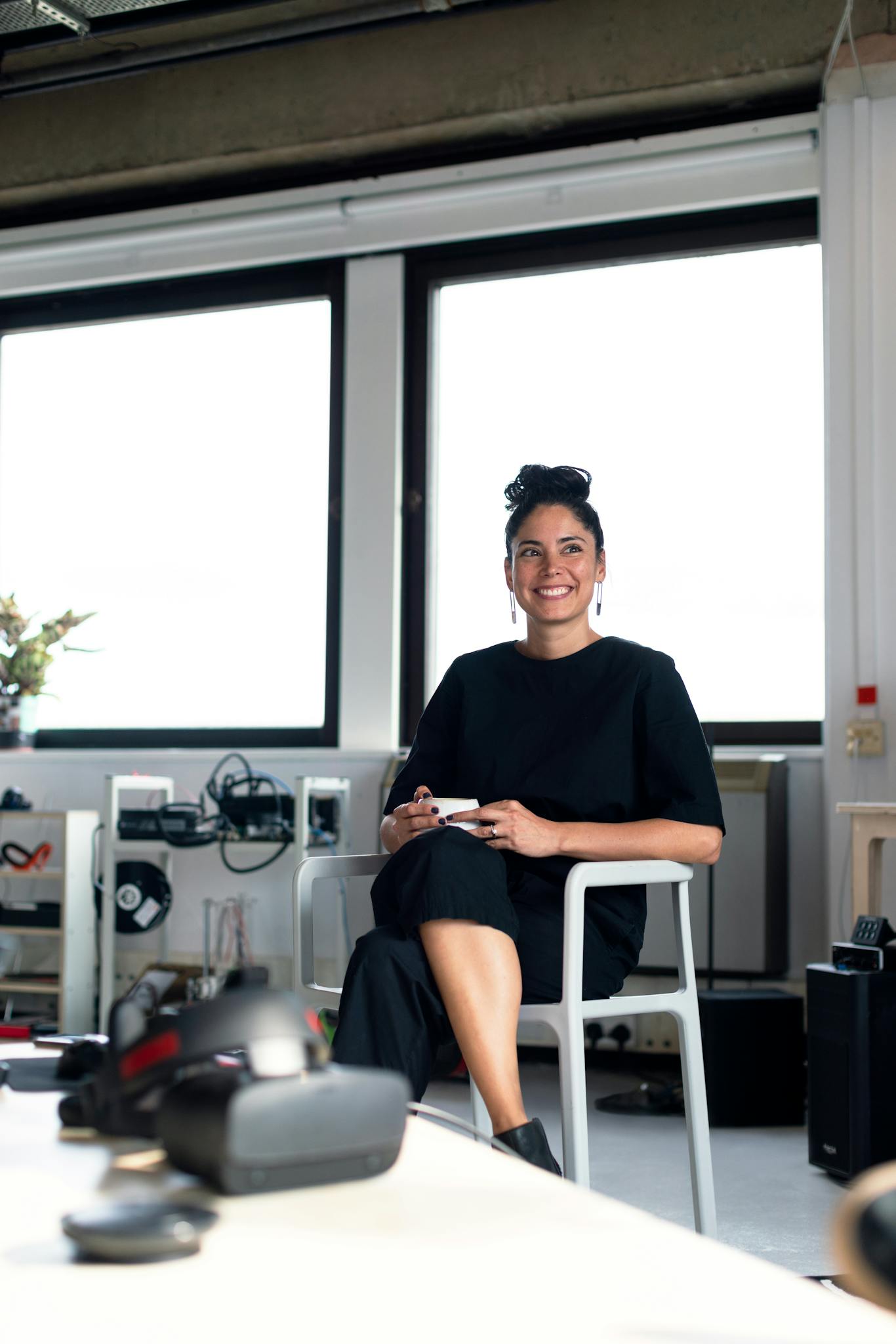 Confident young professional woman enjoying a coffee break in a modern office environment.